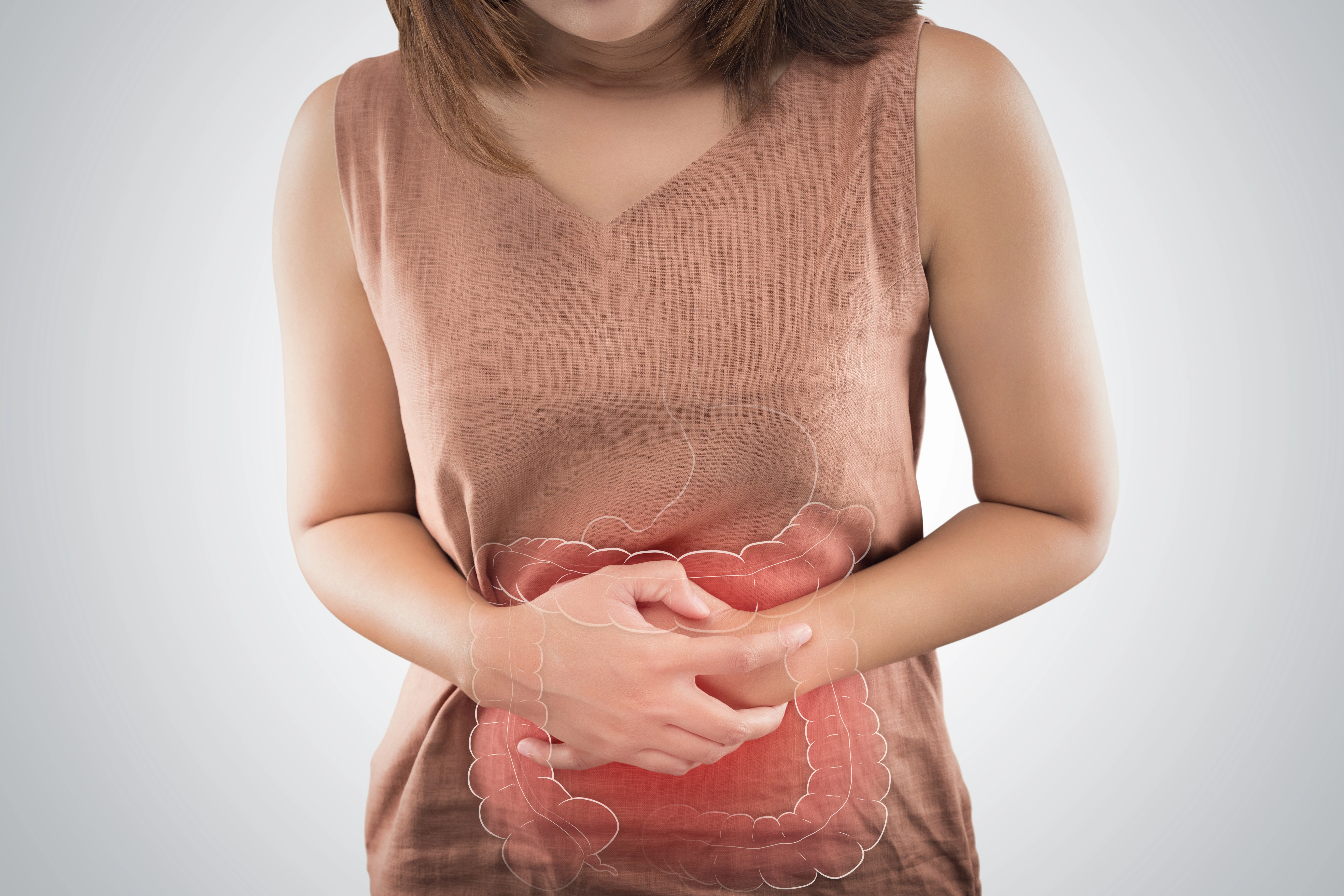 woman holding stomach with diagram of digestive system
