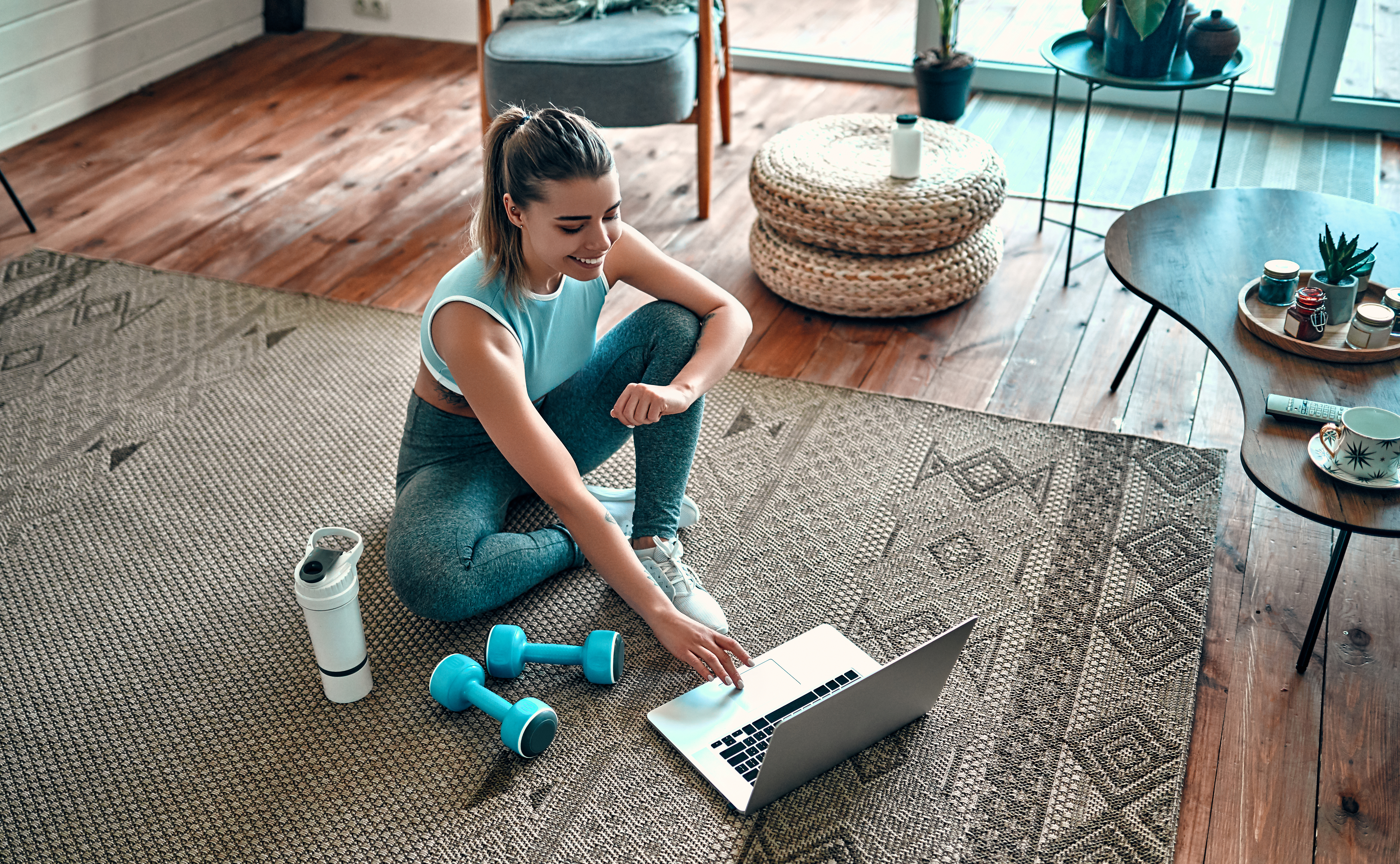 woman with exercise gear looking up workouts on laptop